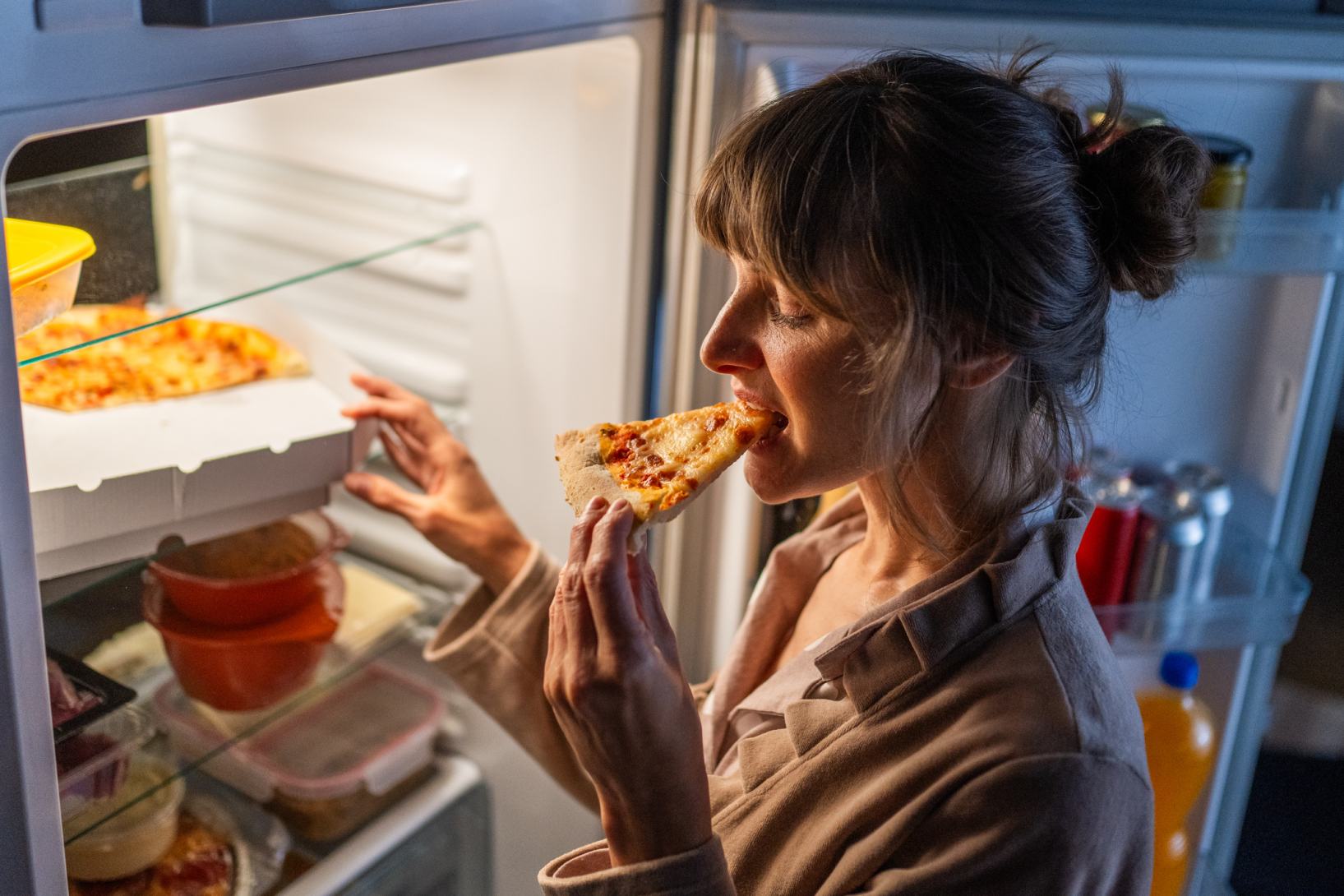 donna mangia pizza dal frigorifero